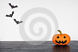 Halloween jack o lantern on a black shelf against a white wall with bats