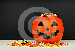 Halloween Jack o Lantern bucket filled with candy against a black background