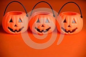 Halloween jack-o-lantern candy buckets or pail on orange background