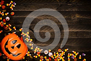 Halloween Jack o Lantern pail with corner border of spilling candy over dark wood