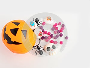 Halloween Jack o Lantern pumpkin bucket, Mashmallow in shape skull, candies and spiders on white background.
