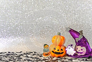 Halloween jack o lantern pumpkin and witches hat with smiling ghost  on  a glitter silver background.