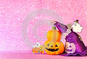 Halloween jack o lantern pumpkin and witches hat with smiling ghost  on  a glittering pink background.