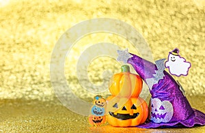 Halloween jack o lantern pumpkin and witches hat with smiling ghost  on  a shiny golden background.