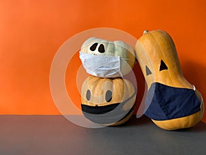 Halloween jack o lantern pumpkins wearing a medical face masks as protection against virus infection and coronavirus