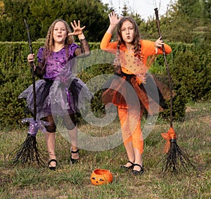 Halloween kid girls costume witches scaring gesture in outdoor.