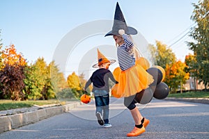 Halloween kids. Brother and sister in carnival costumes celebrating Halloween outdoors. Boy and girl in witch hat with