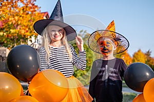 Halloween kids. Brother and sister in carnival costumes outdoors. Boy and girl in witch hat with pumpkin candy buckets