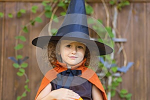 Halloween kids. funny cute smiling girl in orange witch costume, black hat with pumpkin Jack,
