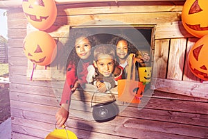 Halloween kids in playhouse window with buckets