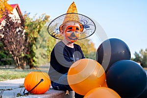 Halloween kids. Portrait smiling boy in witch hat with orange and black balloons. Funny kids in carnival costumes