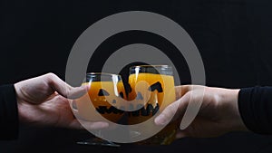 Halloween. linking glasses of juice. Black background.