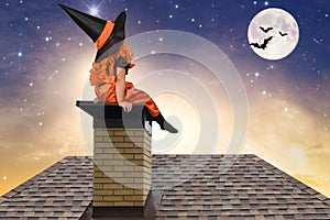 Halloween.Little girl in a witch costume sitting on the roof and looks at the sky.