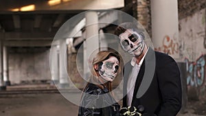 Halloween loving couple in costumes of skeletons and sugar skull make-up.