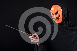 Halloween man with pumpkin mask holding magic wand