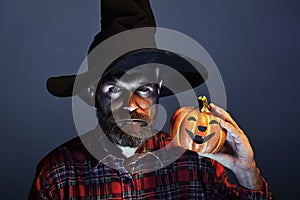 Halloween man in witch hat holding pumpkin on blue background