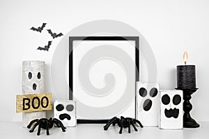 Halloween mock up black frame on a white shelf with rustic wood ghost decor, spiders and black candle