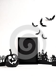 Halloween mock up. Black photo frame and paper art  abandoned village, pumpkin on white background