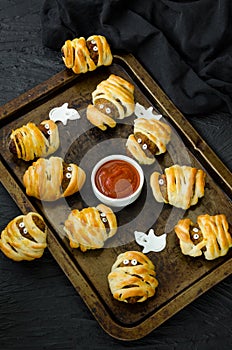 Halloween mummies - meatballs wrapped in dough with spicy tomato sauce on an old baking sheet.