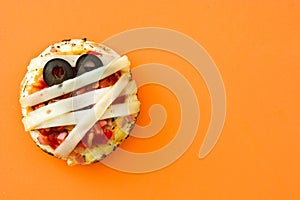 Halloween mummies mini pizzas on orange background