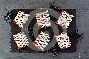 Halloween mummy brownies, top view with spiders on a slate platter