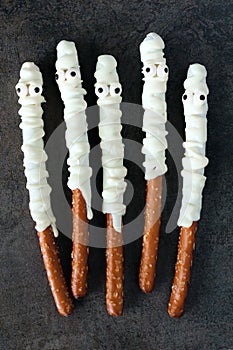 Halloween mummy, candy dipped pretzel rods on black stone