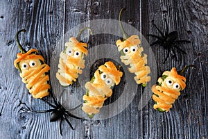 Halloween mummy jalapeno poppers, top view on old wood
