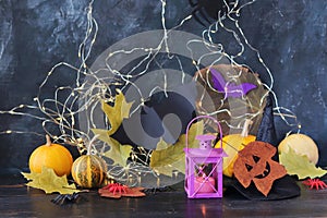 Halloween mystical decor, lantern with burning candle, autumn leaves on a black background, decorated home interior for the holida