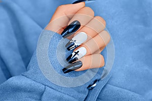 Halloween nail design with blue shade color with cross. Female hand with autumn manicure, top view. Halloween concept