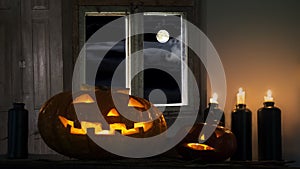 Halloween night, the moon with clouds in the window, pumpkins, candles. Cinemagraph