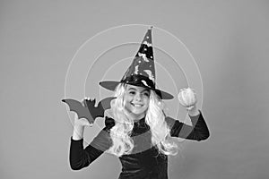 On Halloween night youre sure to have fright. Halloween girl in witch hat orange background. Little girl hold Halloween