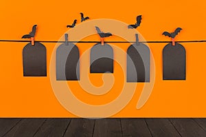 Halloween orange mock up background. Blank black sale labels tomb hanging on clothespins, flock bats and wooden board shelf. Templ