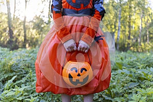 Halloween Parade Children. Child in a witch costume. Girl in orange dress with pumpkin pattern. Children collect treat