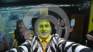Halloween party, night, portrait of a man with a green face, wearing a hat, with a terrible makeup , croaks in front of