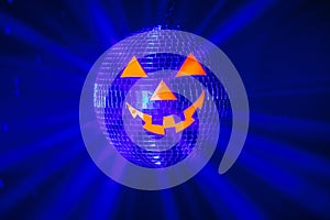 Halloween party pumpkin disco ball, jack o`lantern with shiny rays in smoke