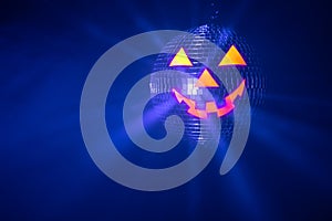 Halloween party pumpkin disco ball, jack o`lantern with shiny rays in smoke