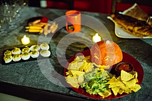 Halloween party snack plate with carved pumpkin, nachos, guacamole and salsa dip