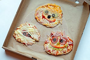 Halloween pizza with monsters, above scene with decor on a craft paper box background, idea for home party food.