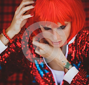 Halloween. Portrait of a beautiful girl in a red wig with horns closeup. Red, festive makeup.