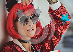 Halloween. Portrait of a beautiful girl in a red wig with horns closeup. Red, festive makeup.