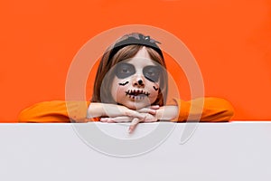 Halloween. Portrait of a girl made up on an orange background