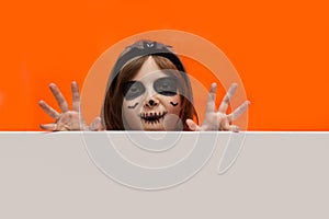 Halloween. Portrait of a girl made up on an orange background