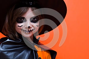 Halloween. Portrait of a girl made up on an orange background