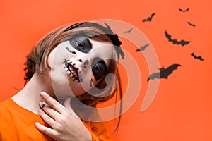 Halloween. Portrait of a girl made up on an orange background