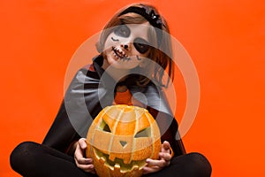 Halloween. Portrait of a girl made up on an orange background