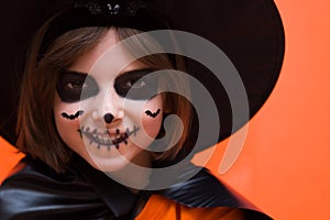 Halloween. Portrait of a girl made up on an orange background