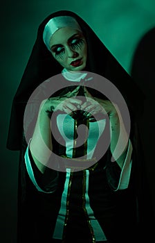 Halloween. Portrait of a scary devilish nun eyes looking at camera on a black and green background.