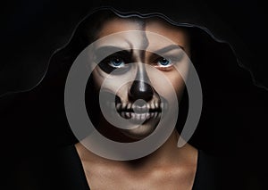 Halloween portrait of young beautiful girl in a black hood. skeleton makeup