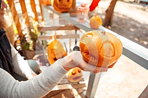 Halloween Preparaton Concept. Young man decorating house with jack-o`-lantern holding pumpkin close-up