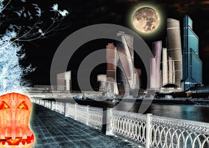 Halloween pumpkin on background of high buildings with river reflections under night glowing Moon in Moscow